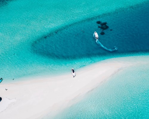 Aerial view of speedboat turning around near a small white-sand beach
