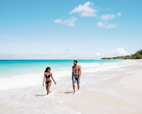 Couple walking along white sand tropical beac