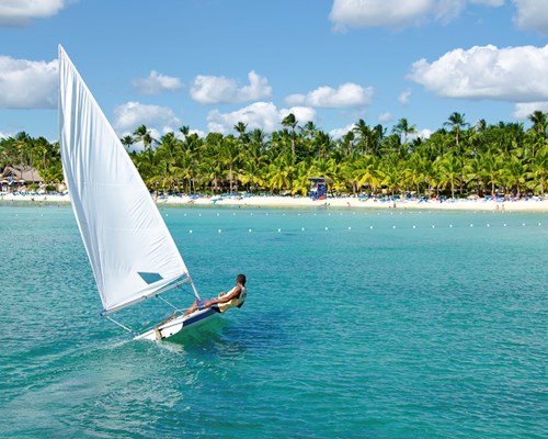  Solo sailing boat near the coast of a white sand tropical beach