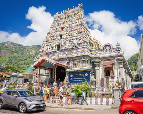 Colourful temple in bustling city with hilly green forest in background