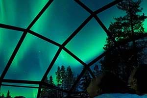 Couple watching the Northern Lights in a glass igloo