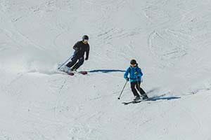 2 skiers skiing down a piste close to each other