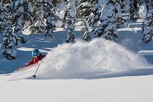 Women in red ski coat skiing through fresh snow